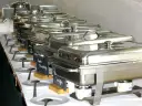 Długi rząd podgrzewaczy z jedzeniem, gotowych do serwowania. To świetny pomysł, jak otworzyć catering i zaimponować gościom.