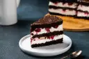 Pyszny tort z mascarpone i owocami, przełożony ciemnym biszkoptem i polany czekoladą. Idealny na deser.