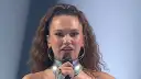 Kto jedzie na Eurowizję? Młoda artystka z mikrofonem, w futurystycznym stroju i z burzą loków, gotowa podbić scenę.
