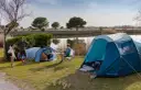 Przyjemny dzień na polu namiotowym nad jeziorem. Ludzie relaksują się, grają w gry i cieszą się naturą.