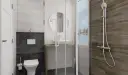 Nowoczesna łazienka z białym WC, umywalką i prysznicem z drewnianą ścianą.