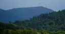 Górzyste krajobrazy czeskich Izery, z zalesionymi zboczami i skalistym szczytem zaznaczonym czerwoną obwódką.
