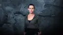 Natalia Brudniak w wojskowym stylu, z rękami w kieszeniach, na tle zniszczonej ściany.