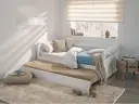 Cama nido blanca con colchones, cojines y manta en un dormitorio juvenil.
