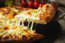 Gorąca pizza z ciągnącym się serem, idealna do pizzy, z pomidorami w tle.