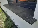 Elegancki, ciemny rodzaj zewnętrznego parapetu z kamienia, ozdobiony kwitnącą lawendą.