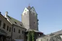Kamienny zamek Loket z wieżą i budynkami mieszkalnymi pod błękitnym niebem.