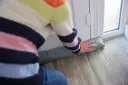 Osoba zakłada na drzwi materiałowy izolator przeciwwilgociowy.