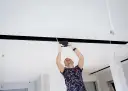 Montażysta instaluje oświetlenie LED w nowoczesnym suficie podwieszanym z wnęką.