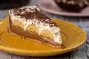 Kawałek banoffee pie z bananami, kremem i czekoladą na żółtym talerzu. Nie tarta cytrynowa, ale pyszny deser!
