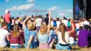 Widok zza pleców na tłum ludzi na jednym z największych festiwali muzycznych w Polsce. Słońce, niebo i dobra zabawa.
