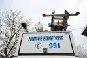 Tył białego samochodu pogotowia energetycznego z napisem "POGOTOWIE ENERGETYCZNE 991" i drabiną na dachu.
