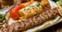 Kebab na talerzu z warzywami i plackiem.