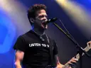 Jason Newsted z zespołu, w czarnej koszulce z napisem "LISTEN TO N", śpiewa do mikrofonu, grając na basie.
