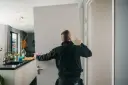 Pracownik montuje drzwi, tworząc wykucie otworu na drzwi w nowoczesnym wnętrzu.
