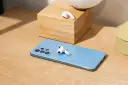 AirPods liegen auf einem blauen Samsung-Smartphone und einem Holzblock.