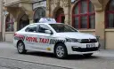 Biała taksówka Royal Taxi z numerem 260 na tle zabytkowej kamienicy we Wrocławiu.