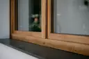 Drewniane okna w ciepłym kolorze okien winchester, z kamiennym parapetem.