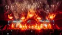 Spektakularny pokaz fajerwerków i płomieni na scenie podczas festiwalu Sunrise Festival 2026. Tłum ludzi z telefonami wzniesionymi ku górze.