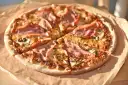Pizza z szynką i pieczarkami, idealna na szybki obiad. Jakie pieczarki do pizzy? Te ciemne, pokrojone w plasterki, świetnie komponują się z serem i wędliną.
