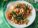 Pad thai z krewetkami, kalmarami, kiełkami i orzechami nerkowca. Widać też kawałek limonki, idealne pad thai składniki.