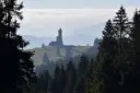 Widok na dalimilova rozhledna górującą nad mglistym krajobrazem, otoczona lasem iglastym.