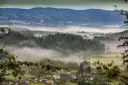 Mgliste poranki nad Sudetami. W oddali widać zamek, a niżej rozciągają się lasy i urokliwe miejscowości.