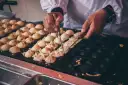 Ręce obracają kulki takoyaki na specjalnej patelni. Ten prosty takoyaki przepis jest w trakcie realizacji.