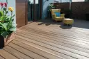 Drewniany taras z żółtym fotelem i pufą. Idealne miejsce do relaksu, gdy zastanawiasz się, czym wyłożyć taras tanio.