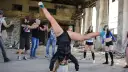 Grupa młodych ludzi tańczy w opuszczonym budynku. Jedna z dziewczyn wykonuje efektowną figurę, stojąc na rękach. To właśnie dancehall!