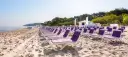 Rzędy fioletowych leżaków na piaszczystej plaży nad morzem.