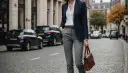 Elegancka stylizacja: granatowa marynarka, biała koszula i brązowa torebka to idealne dopełnienie tego, co pasuje do szarych spodni damskich.