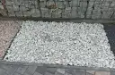 Biały grys na podjeździe obok gabionów i kostki brukowej.