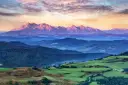 Tatry o zachodzie słońca, jedno z 5 najpiękniejszych miejsc w Polsce. Góry w odcieniach różu i fioletu, zalesione wzgórza i zielone pola.
