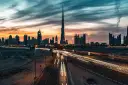 Wieczorny widok na Dubaj z Burj Khalifa, gdzie światła samochodów tworzą smugi na autostradzie. Ciekawostki o tym drapaczu chmur mogą dotyczyć jego wysokości i budowy.