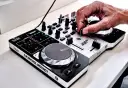 Dłoń DJ-a miksuje szybkie piosenki do tańca na kontrolerze Hercules DJControl Instinct.