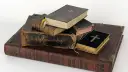 Stapel alter Bücher, einige mit Kreuzen auf dem Einband.