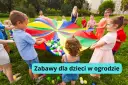 Dzieci bawią się kolorowym spadochronem z piłeczkami w ogrodzie. Radosne kreatywne zabawy w ogrodzie.