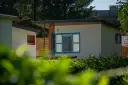 Nowoczesne domki letniskowe w osadzie Chmielaki. Jasne ściany, niebieskie okna i drewniane elementy tworzą przytulną atmosferę.