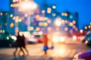 Rozmazane światła miasta i sylwetki ludzi na ulicy.