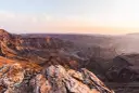 Wąwóz Fish River w Namibii, z rzeką wijącą się w dole. Zachodzące słońce maluje skały na ciepłe barwy.