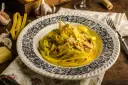 Makaron tagliatelle w kremowym sosie curry z kurczakiem i porem, ozdobiony szczypiorkiem.