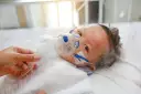 Dziecko z maską tlenową, być może z powodu RSV. Co to jest RSV? To wirus, który może być groźny dla najmłodszych.