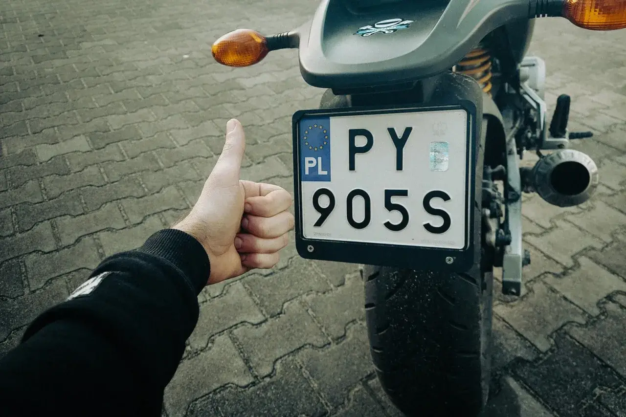 Kciuk w górę przy rejestracji starego motocykla z dokumentami. PY 905S.