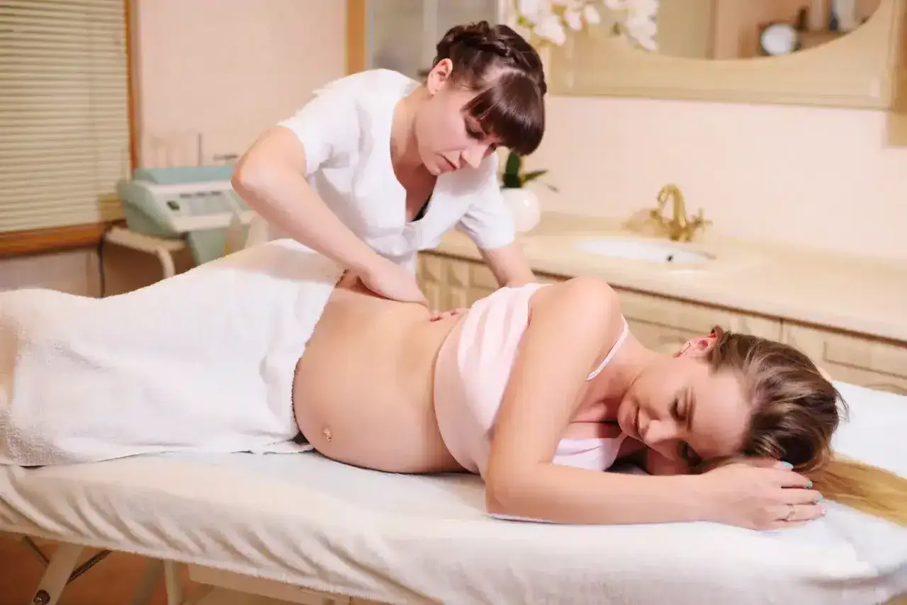 Relaksacyjny masaż w ciąży dla przyszłej mamy. Terapeuta delikatnie masuje plecy, przynosząc ulgę.