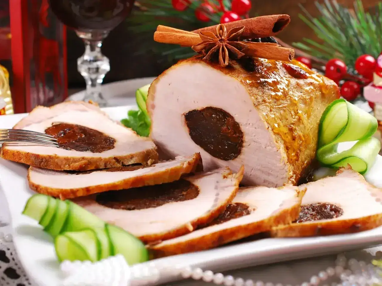 Pyszny schab ze śliwką, pieczony z przyprawami, podany z ogórkiem i dekoracjami świątecznymi.