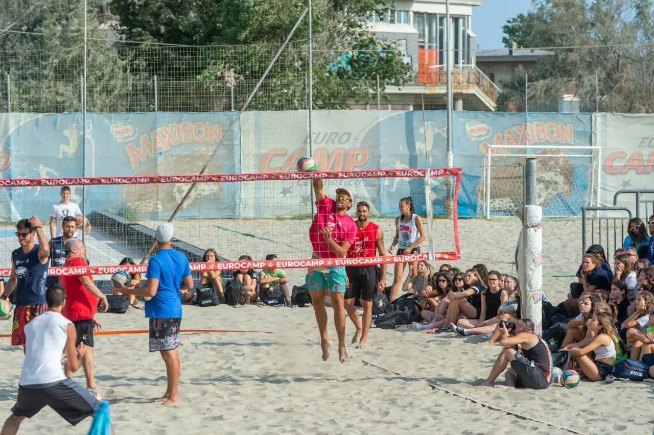 Partita di camp volley Cesenatico: un giocatore salta per colpire la palla mentre gli spettatori osservano.
