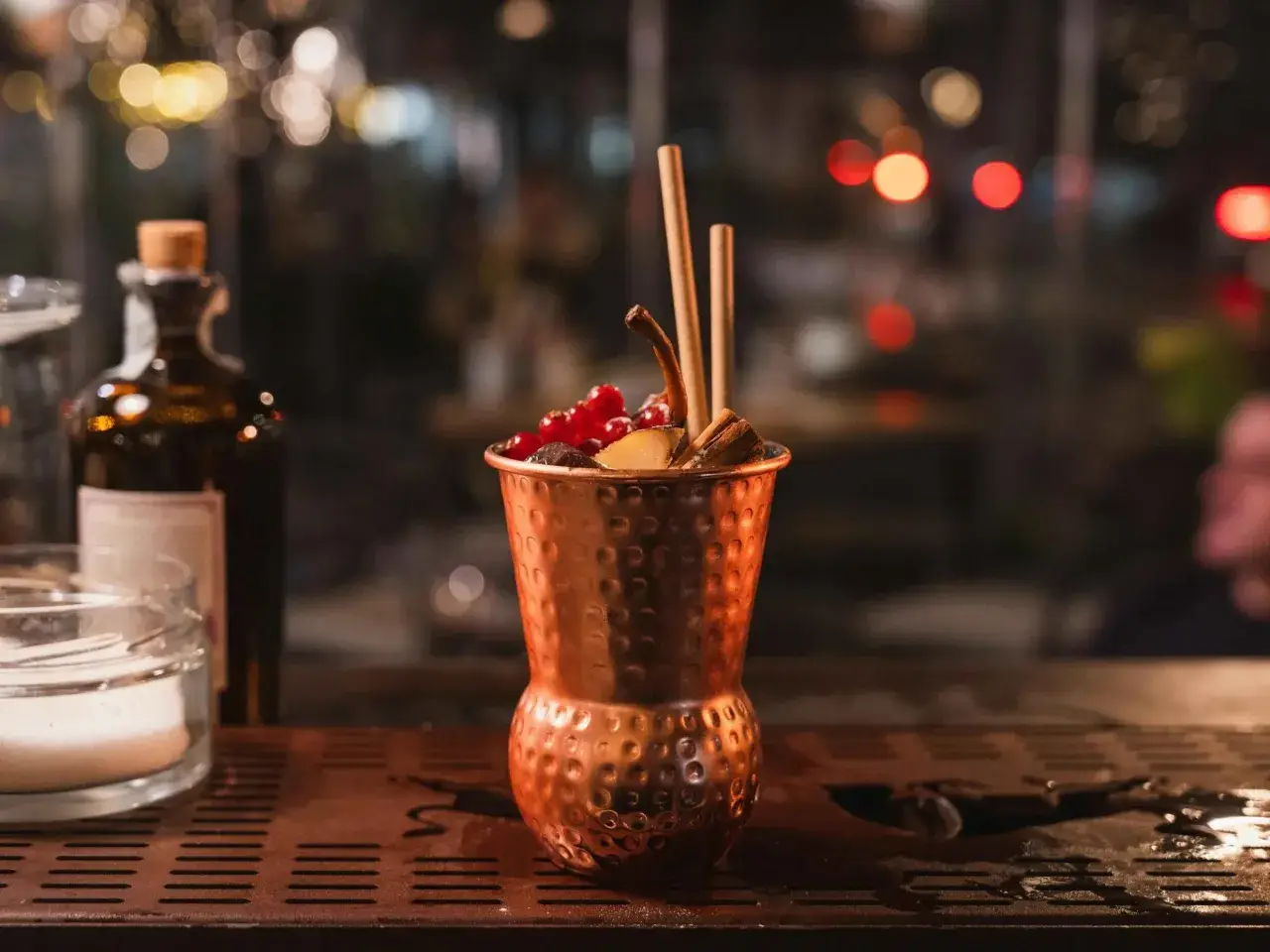 Cocktail in rame, decorato con frutti rossi e cannella, perfetto per un aperitivo Milano Marittima.