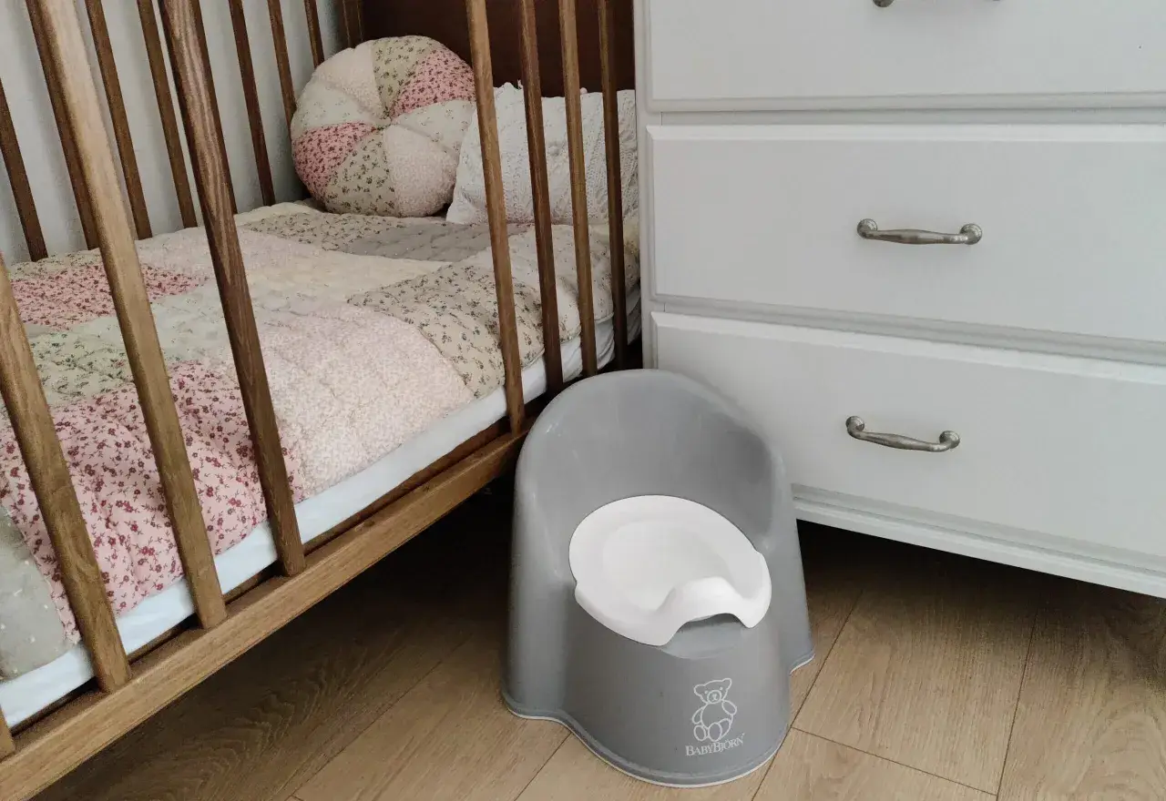 Szara nocniczka BabyBjörn obok łóżeczka. Czas na rozwiązanie problemu z odpieluchowaniem 3 latka.