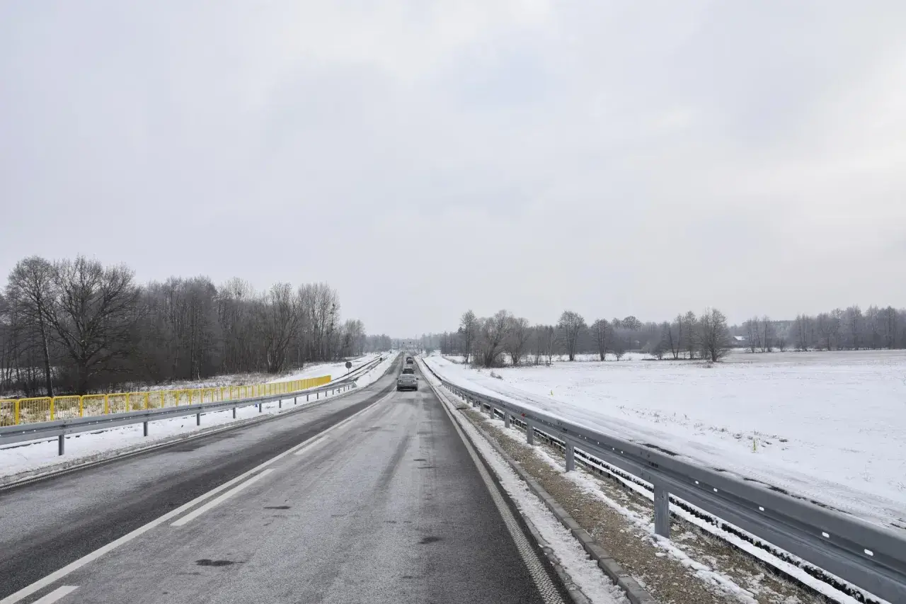 Zimowa trasa, śnieg przy drodze, drzewa bez liści. Nowy tomyśl trasa wita podróżnych.